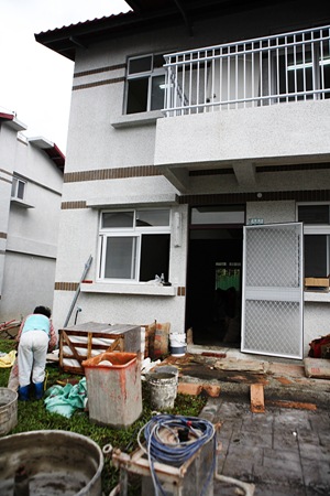 許多永久屋前堆滿了水泥預拌工具、木工器械、磁磚、地磚、水泥包，準備將新居改造成更符合他們需求的寓所